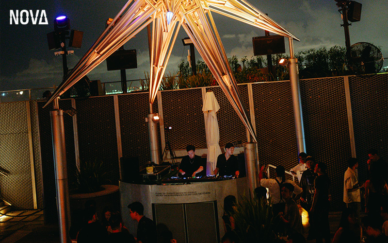 Nova rooftop bar with a DJ and crowd.