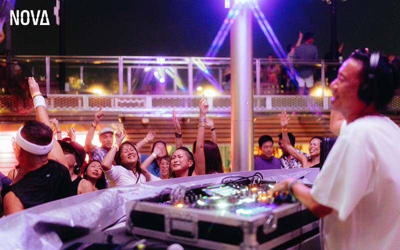 DJ performing for a lively crowd at Nova Bar.
