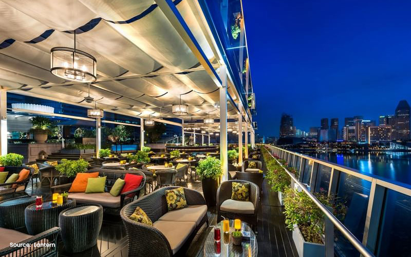 Lantern rooftop bar with Singapore skyline view.
