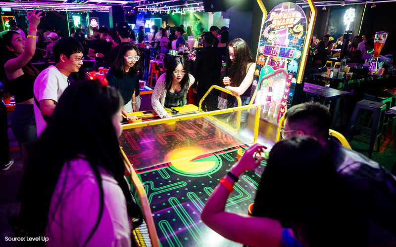 People playing arcade games at Level Up, a music bar.